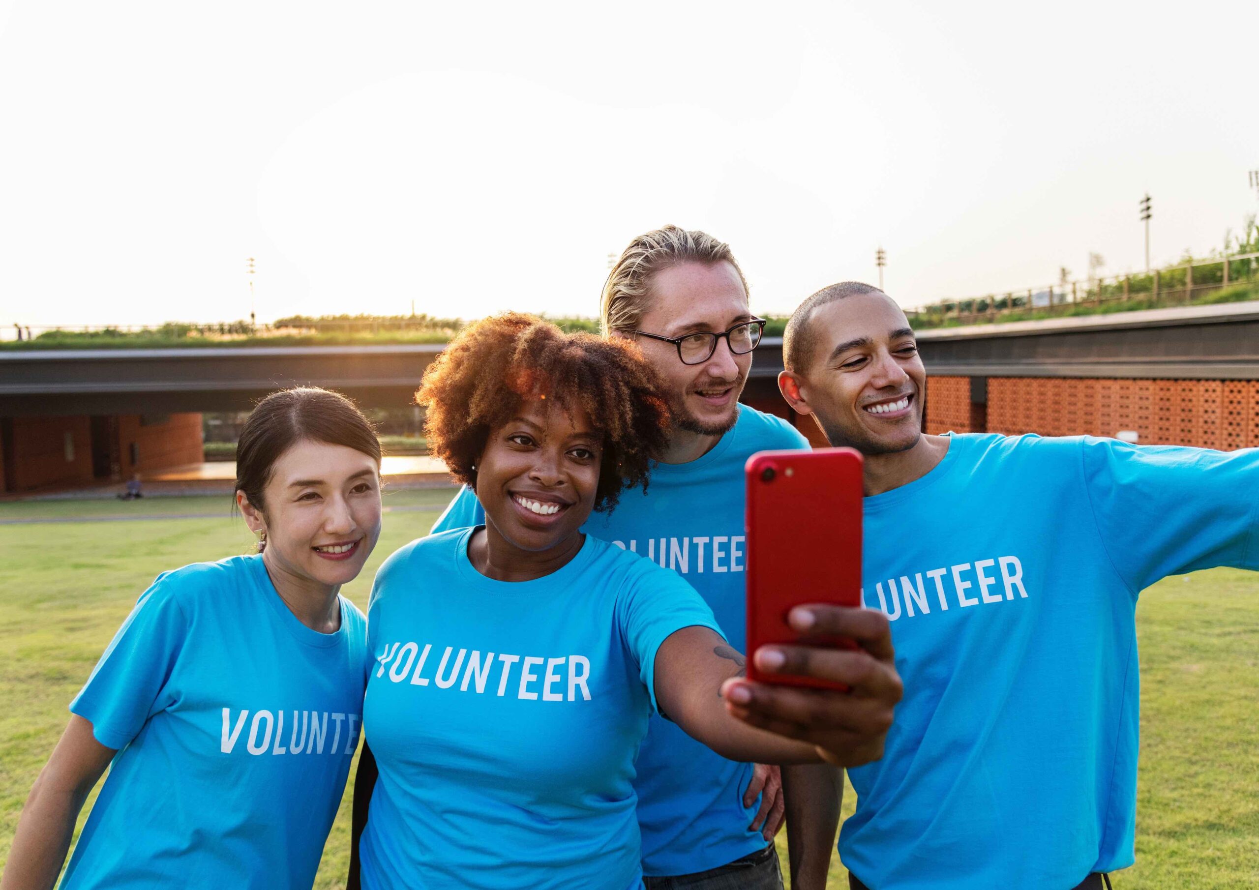 Body Avoidance and Photos in eating disorder recovery in California [Image description: photo of 4 diverse people in "volunteer" shirts taking a selfie] represents a potential client with an eating disorder in Los Angeles, California staying in the photo