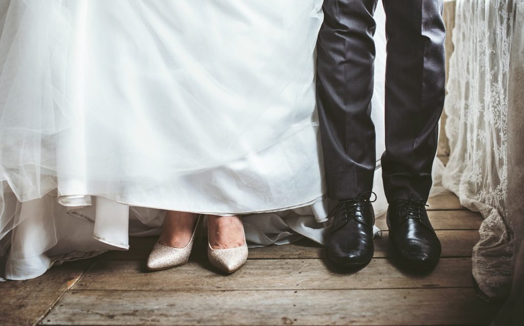 Sweating for the Wedding? Say: I Don’t. Image description: photo of the ankles and feet of a bride in a white gown with white shows and a groom with black pants and black shoes] Represents a potential person in Los Angeles, California preparing for a wedding.