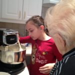 Cultural connection through food and eating disorder recovery in Los Angeles, California [Image description: photo of an old woman watching a young girl operate a mixer making poundcake]