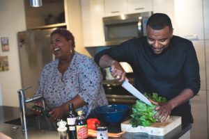Regular Eating in Eating Disorder Recovery in Los Angeles [photo description: a black couple smiling as they wash and cut vegetables] Represents a possible person in recovery from an eating disorder engaging in regular eating in Los Angeles, CA.