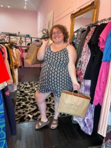 Sharon Maxwell shopping while fat in recovery in Los Angeles, California [Image description: photo of a happy fat woman holding clothing at the Plus Bus in Los Angeles, CA]