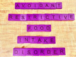 Avoidant Restrictive Food Intake Disorder in Los Angeles, CA [Image description: Purple scrabble tiles spelling "Avoidant Restrictive Food Intake Disorder"]