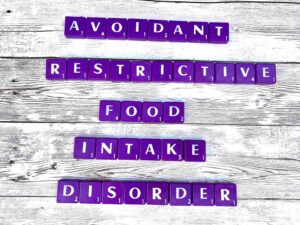 Avoidant Restrictive Food Intake Disorder in Los Angeles, CA [Image description: Purple scrabble tiles spelling "Avoidant Restrictive Food Intake Disorder"]