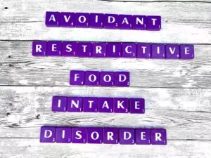 Avoidant Restrictive Food Intake Disorder in Los Angeles, CA [Image description: Purple scrabble tiles spelling "Avoidant Restrictive Food Intake Disorder"]