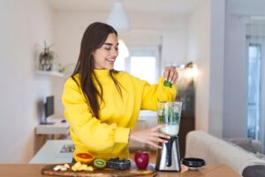 Orthorexia treatment in Los Angeles, California [Image description: photo of a young white woman with long brown hair wearing a yellow sweat suit making a fruit smoothie in a blender] Represents a potential client with Orthorexia or an eating disorder seeking counseling in Los Angeles, California