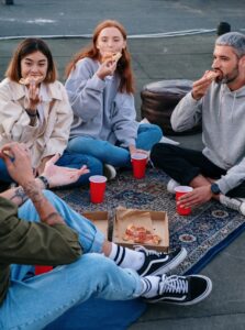 College Students in California demonstrating readiness after an eating disorder [Image description: photo of college students on the ground eating pizza] Represents potential college student in California in recovery from an eating disorder