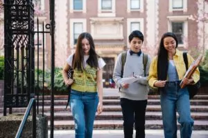 College Students in California [Image description: photo of 2 young woman and a young man walking on a college campus] Represents potential college students who have overcome eating disorders