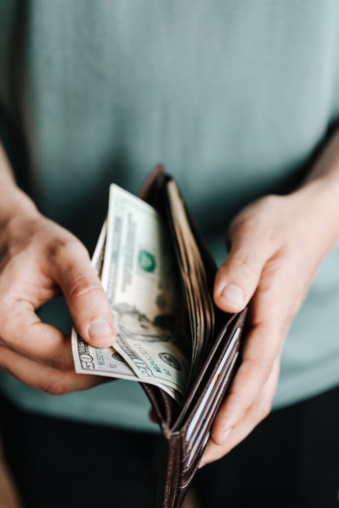 Paying for eating disorder therapy [Image description: a man's hands pulling money out of a wallet] Represents someone paying for therapy in California