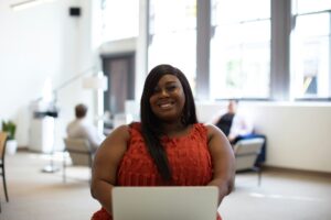 Potential Bariatric Surgery Client in Californai [Image description: a black woman in a larger body smiling and sitting in a waiting room]