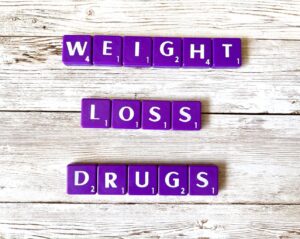 Weight Loss Drugs [Image description: purple scrabble tiles spelling "weight loss drugs"]