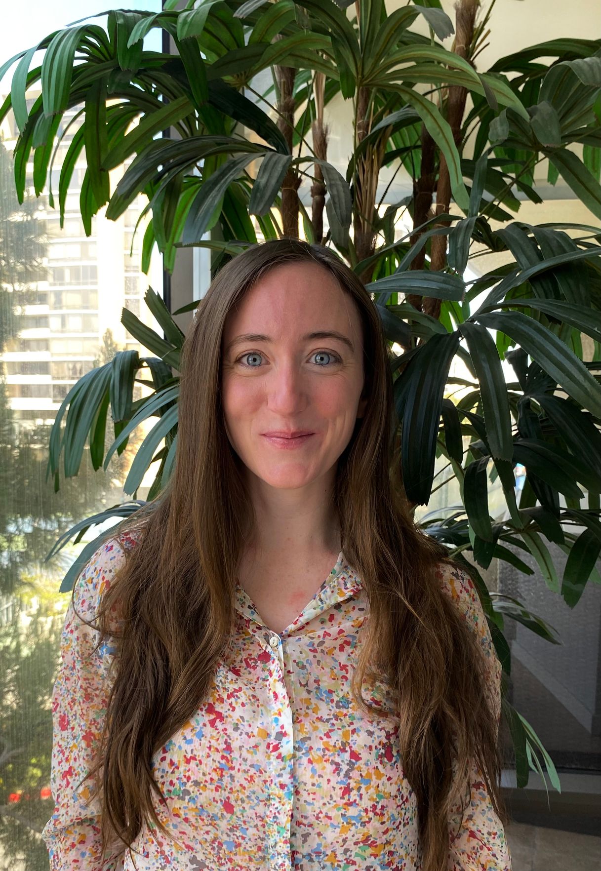 Emma Haren, AMFT [Image description: a young woman with long brown hair, who is an eating disorder therapist at Eating Disorder Therapy LA, smiling in front of a plant]