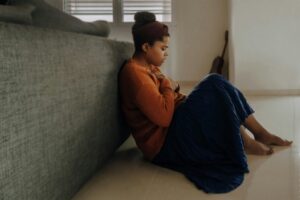 Emetophobia treatment [Image description: photo of woman sitting on floor and holding her check; depicts a potential patient seeking treatment for emetophobia in California.]