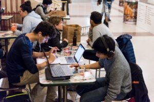 ARFID in College [Image descripton: photo of several college students working on computers and eating; represents potential college students with ARFID in California]